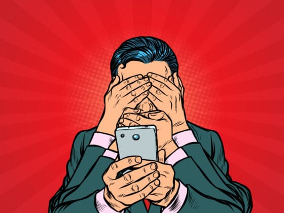 Befogott szemű és szájú ember tart egy telefont